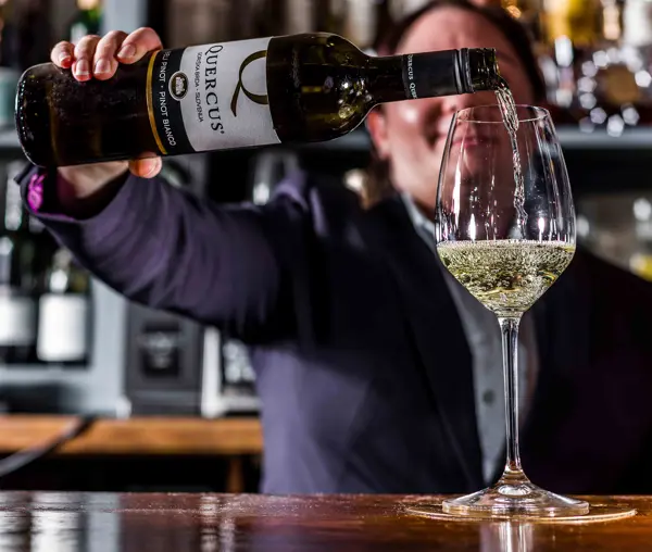 Folk pouring white wine to a glass